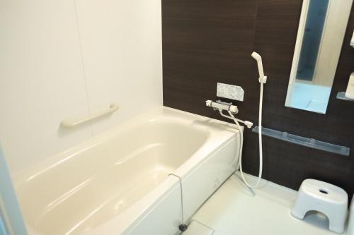 a white bath tub in a bathroom with a mirror at Stay In Biei in Biei