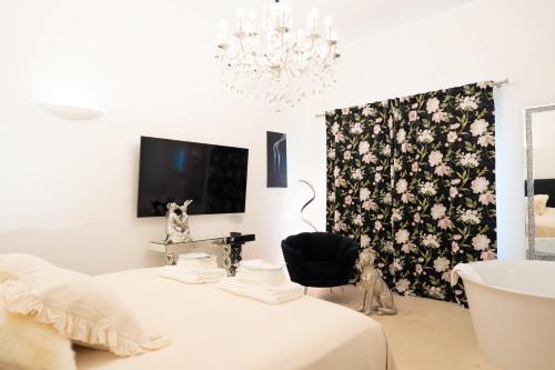 a bedroom with a bed and a chandelier and a bathroom at The White Knight Premium Boutique Hotel in Għajnsielem