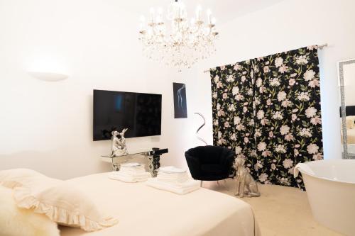 a white room with a chandelier and a bathroom with a tub at The White Knight Premium Boutique Hotel in Għajnsielem