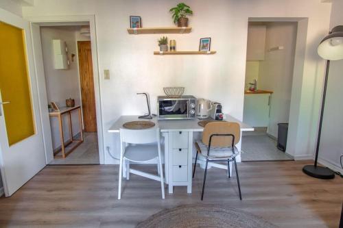 une cuisine avec une table, deux chaises et un four micro-ondes dans l'établissement Marnesia - Studio avec vue sur les quais, à Strasbourg