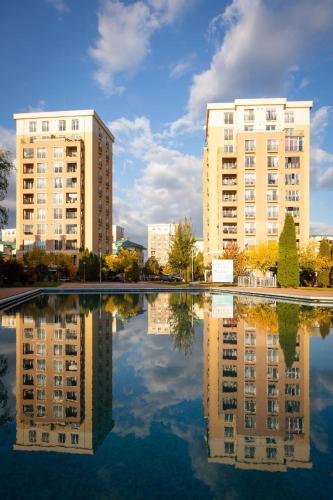 two tall buildings are reflected in a pool of water at Adagio apartment in Creţuleasca