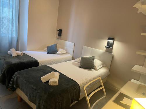 une chambre avec deux lits et une table dans l'établissement Hôtel Anna Livia, à Cannes