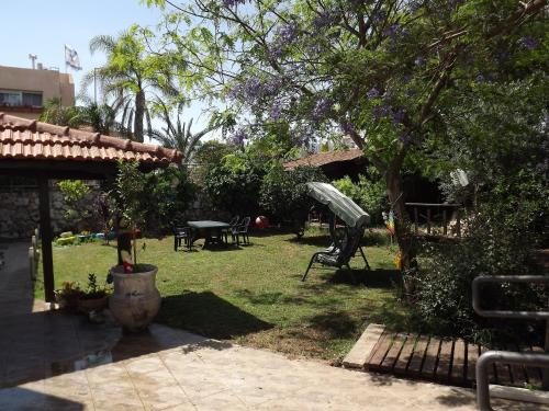 einen Garten mit einer Bank, einem Tisch und einem Baum in der Unterkunft Zimmer In The Garden in Karmi’el