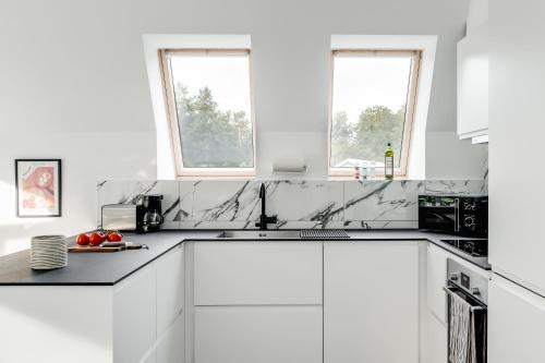 a white kitchen with white cabinets and two windows at Newly built westcoast dream home in Ängelholm
