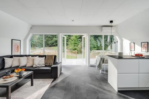 a living room with a black couch and a kitchen at Newly built westcoast dream home in Ängelholm