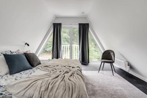 a bedroom with a bed and a chair and a window at Newly built westcoast dream home in Ängelholm