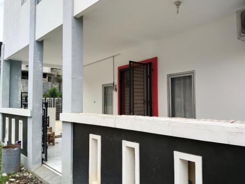 uma vista a partir da varanda de um edifício branco com uma porta vermelha em MyKost Palupuh Valley Syariah em Bogor