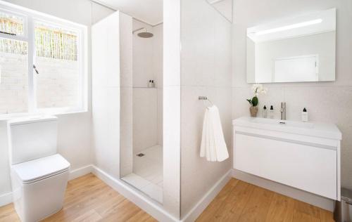 a white bathroom with a shower and a toilet at Middedorp Apartments in Stellenbosch