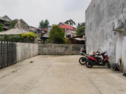 una motocicleta estacionada en un estacionamiento junto a una pared en MyKost Palupuh Valley Syariah, en Bogor
