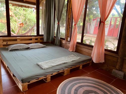 uma cama num quarto com duas janelas em Nhà Gỗ An Trăm Tuổi - Chill Garden Lakeview em Hanói