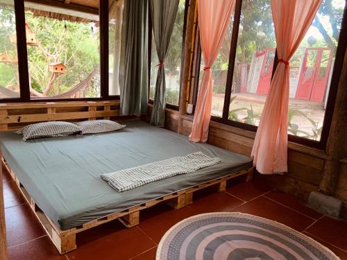 a bed in a room with two windows at Nhà Gỗ An Trăm Tuổi - Chill Garden Lakeview in Hanoi