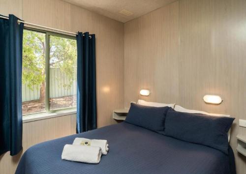 a bedroom with a blue bed with towels on it at Horseshoe Tourist Park in Wagga Wagga