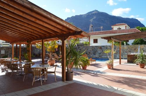 un patio con mesas, sillas y una montaña en Hotel La Aldea Suites, en San Nicolás