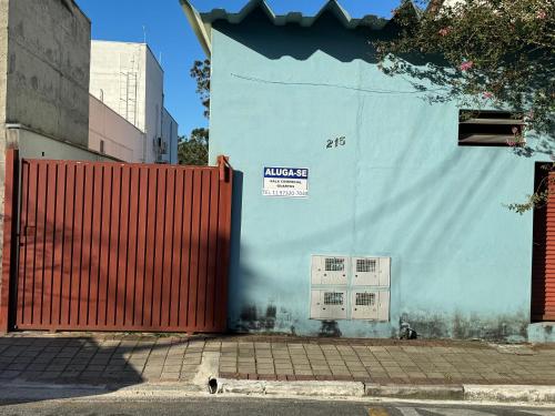 una pared azul con una puerta roja y un edificio en Quarto Laurinda 1, en Guararema