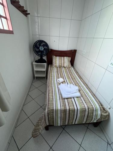 Habitación pequeña con cama y ventilador. en Quarto Laurinda 1, en Guararema