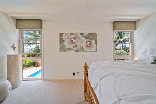 a white bedroom with a bed and two windows at Nani Kai Hale A209 in Kihei
