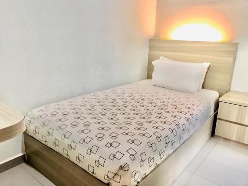 a small bedroom with a bed with a white blanket at Kozi Hotel - Bukit Indah in Johor Bahru