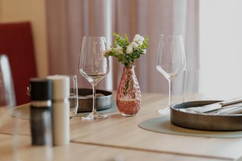 a table with two wine glasses and a vase with flowers at Kloster by b-smart in Schaan
