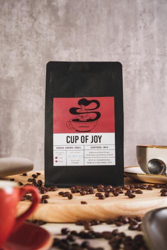 a cup of joy sign on a table with coffee beans at Kloster by b-smart in Schaan