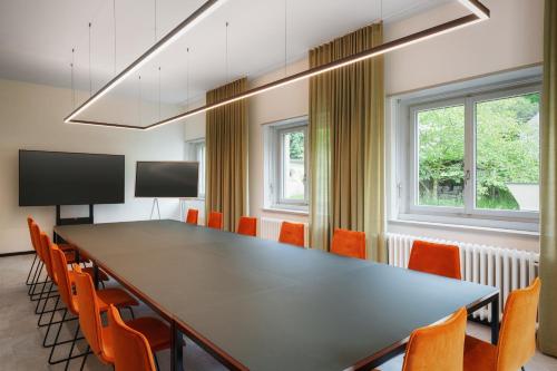 a conference room with a large table and orange chairs at Kloster by b-smart in Schaan
