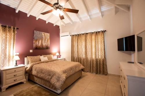 Schlafzimmer mit einem Bett und einem Deckenventilator in der Unterkunft Airport View 3-Bed Villa in Cupecoy