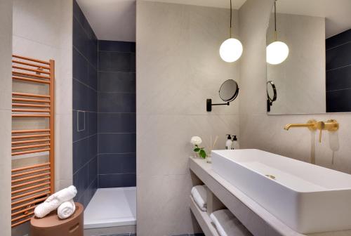 a bathroom with a white sink and a tub at Hôtel Artemisia Montmartre in Paris
