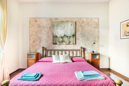 a bedroom with a pink bed with two towels on it at Villa Germana in Castenedolo