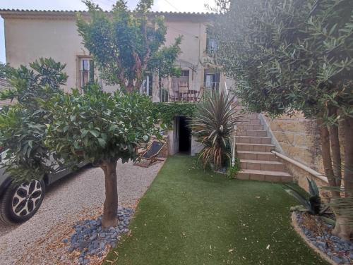 una casa con un patio con árboles y un coche en Le clos de l'Olivelle, en Gallargues-le-Montueux