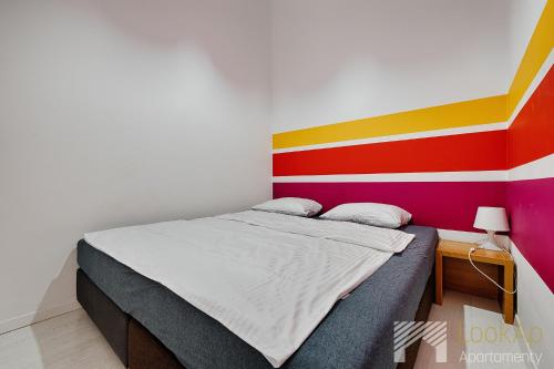 1 cama en una habitación con una pared colorida en Loft Malinowy by LookAp en Lodz