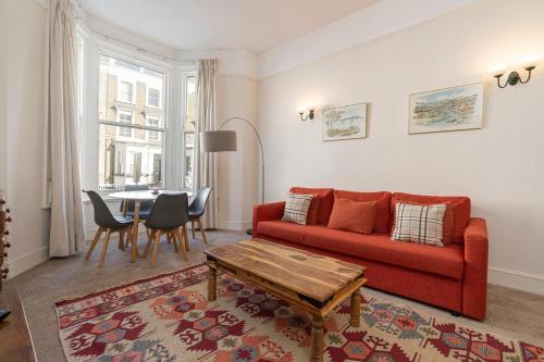 uma sala de estar com um sofá vermelho e uma mesa em Adorable 1 bed flat in West Brompton, sleeps 4 em Londres