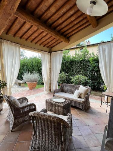 an outdoor patio with wicker chairs and a couch at Dante Country House - Casa con Piscina Privata e Jacuzzi tra Firenze e Chianti in Scandicci