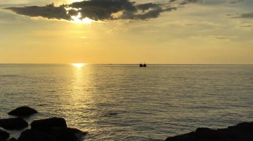 a sunset over the ocean with a boat in the water at On the Rocks in Koh Rong Sanloem