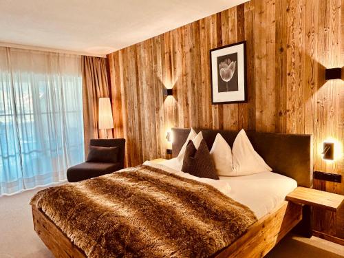 a bedroom with a large bed and a chair at Sonn-Alm Chalet-Apartments in Bichlbach