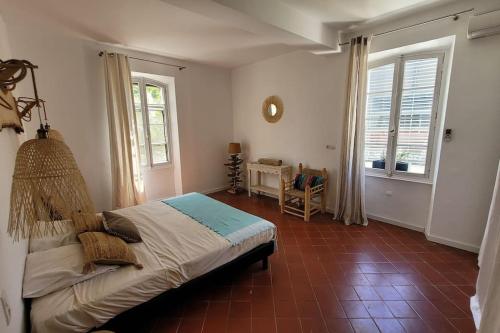 a bedroom with a bed in a room with windows at Maison classée 5 étoiles à 3km de la mer - Wine and Kite in Torreilles
