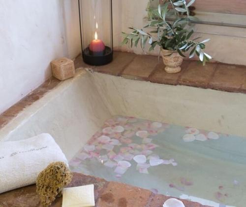 a bath tub with a candle and a flower rug at Maison classée 5 étoiles à 3km de la mer - Wine and Kite in Torreilles