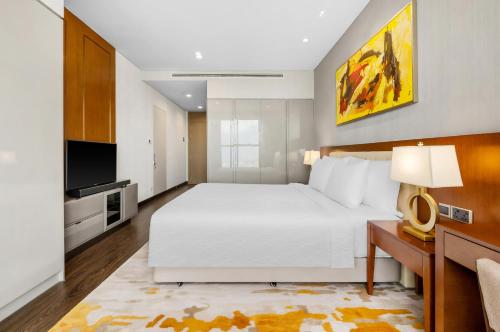 a bedroom with a large white bed and a television at Sedona Suites Ho Chi Minh City in Ho Chi Minh City