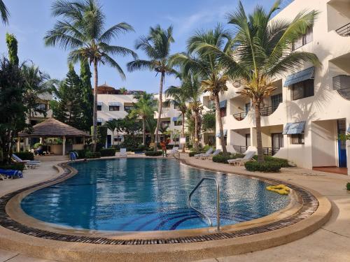 - une piscine dans un complexe avec des palmiers dans l'établissement Appartement "AMINA" mit Pool, à Saly Portudal