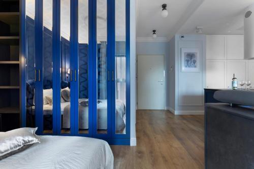 Elite Apartments Grano Residence في غدانسك: غرفة نوم بتقسيم ازرق مع سرير