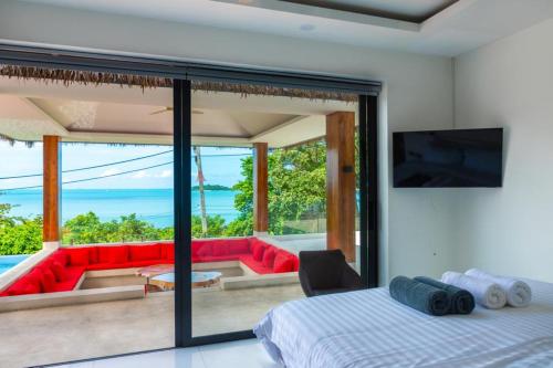 a bedroom with a view of a living room with a red couch at Villa Nirvana - Wonderful Sea View in Koh Samui 