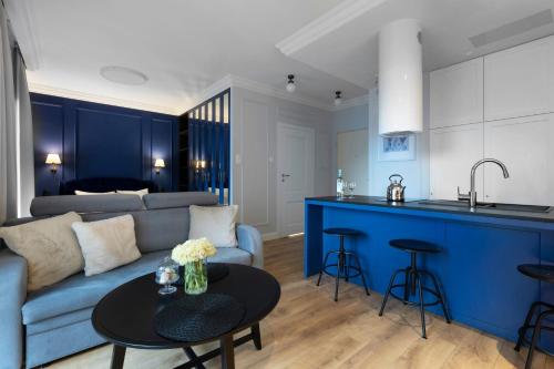 a living room with a blue couch and a table at Elite Apartments Grano Residence in Gdańsk