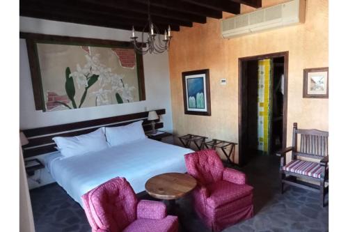 1 dormitorio con 1 cama y 2 sillas rosas en Collection O Posada De Las Flores Loreto en Loreto