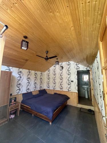 a bed in a room with a wooden ceiling at The Aisling House in Kasol