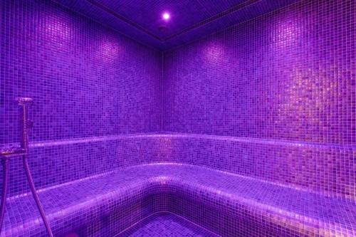 d'une salle de bains pourpre pourvue d'une baignoire avec des lumières violettes. dans l'établissement Ultra All Inclusive Apartament w Amber Park Spa, à Niechorze