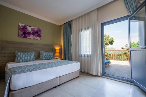 a bedroom with a large bed and a balcony at Bodrum Park Resort in Yaliciftlik