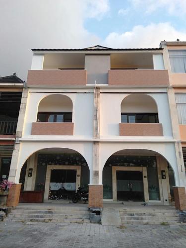 a large white building with arches in front of it at Rumah WJ rooms and suites in Uluwatu
