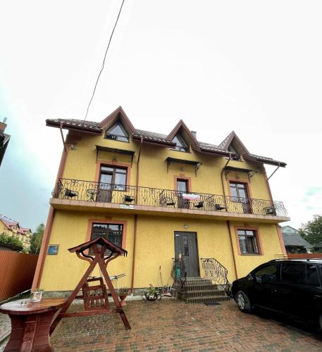 a yellow house with a black car parked in front of it at Вілла Львів in Skhidnitsa