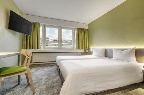 a hotel room with a bed and a desk and a window at flexymotel Wil in Wil