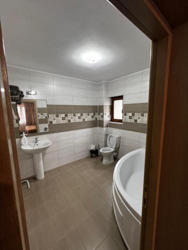 a bathroom with a tub and a toilet and a sink at Casa Bujor de Munte Dragoslavele in Dragoslavele