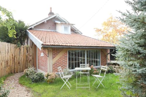 ein kleines Backsteinhaus mit einem Tisch und Stühlen im Hof in der Unterkunft Suite Garden by La Boîte En Plus in Senlis