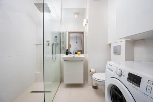 a white bathroom with a sink and a washing machine at Bluszczańska Blue Modern Apartment in Warsaw